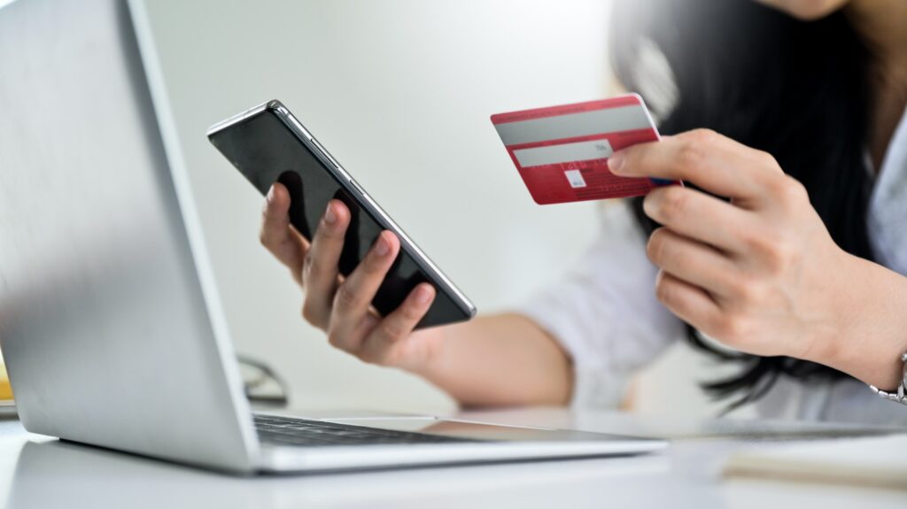 Young woman holding credit card and smartphone with laptop, Credit card payment.